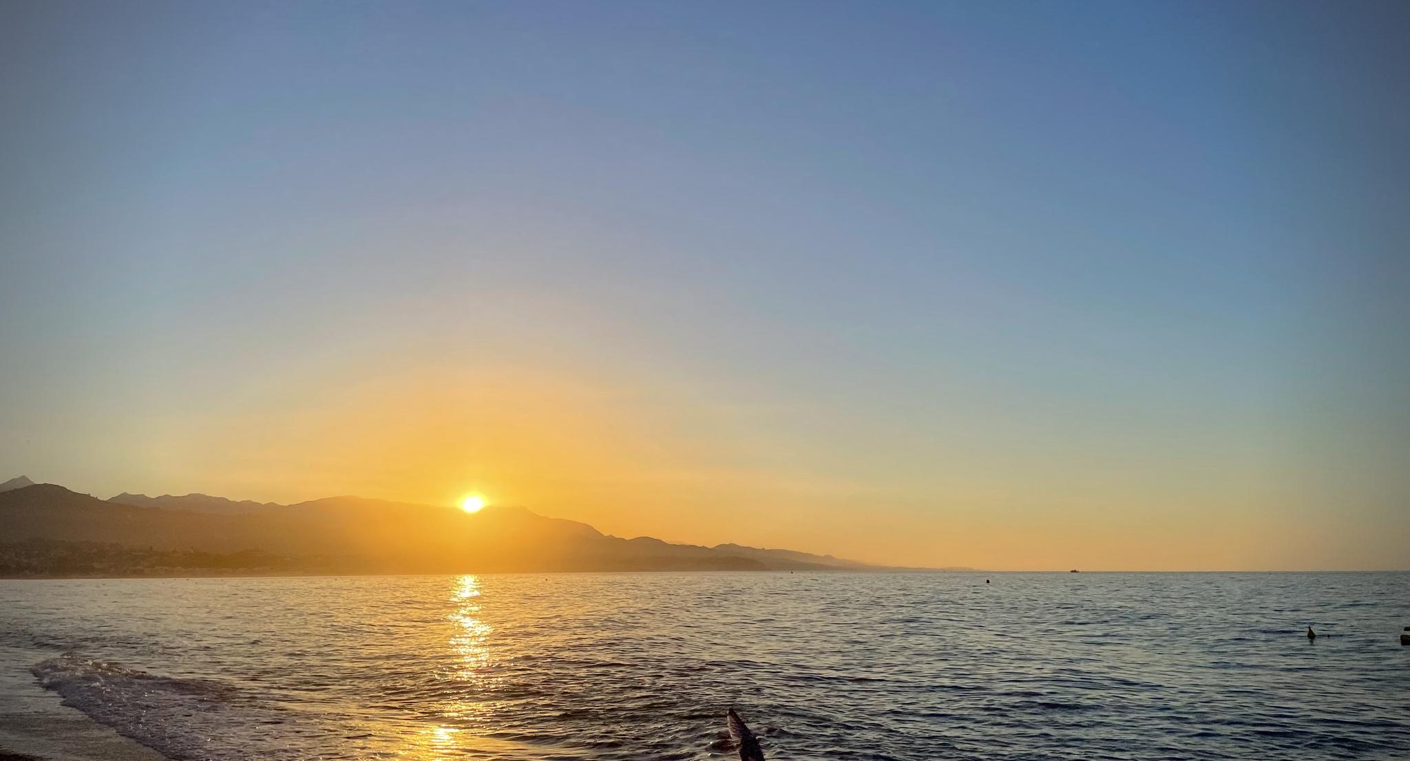 The sun rises over the Sierras de Tejeda, Almijara & Alhama and the Mediterranean Sea in Torre del Mar, Spain.