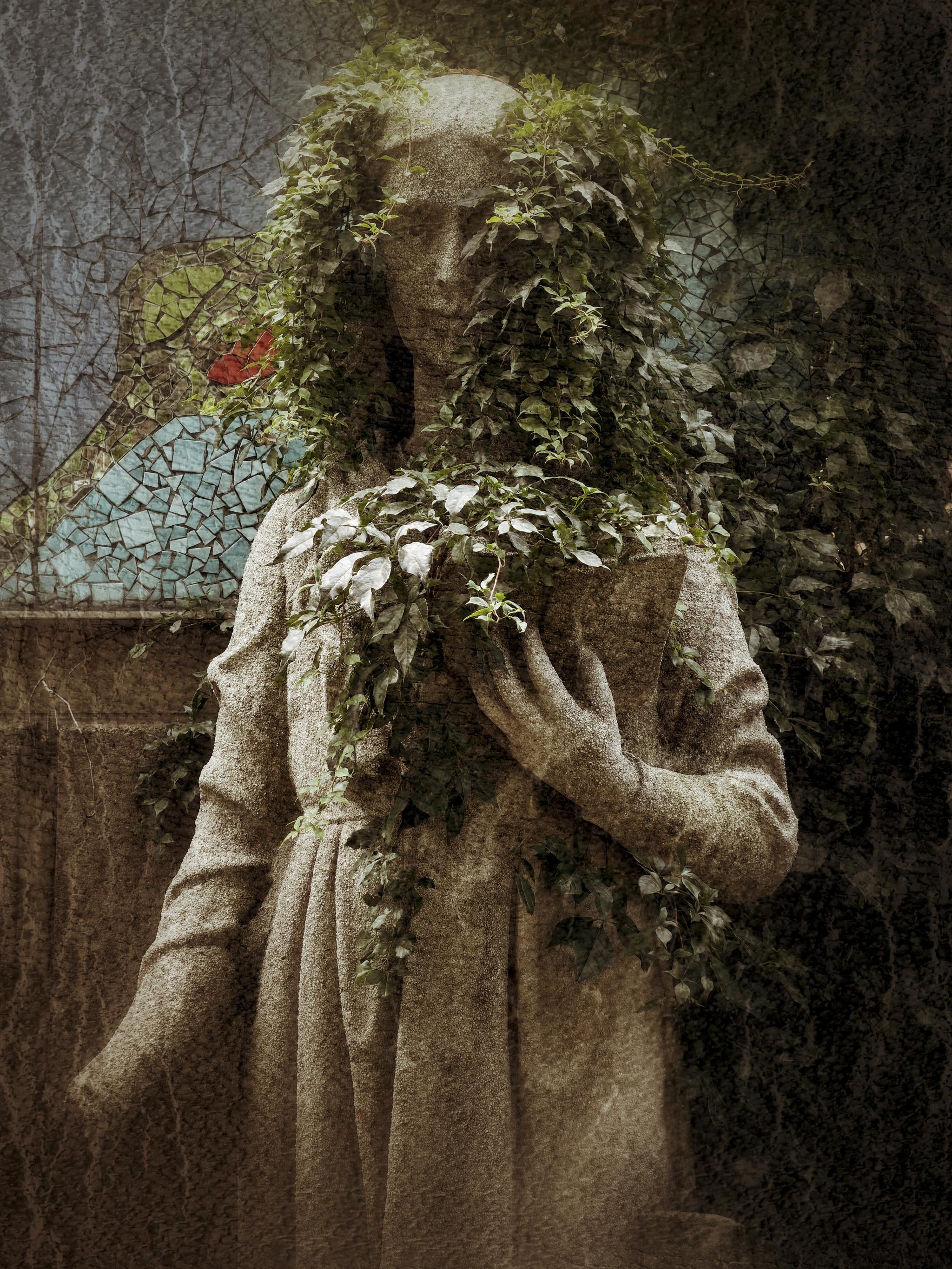 A statue partially covered with leaves.
