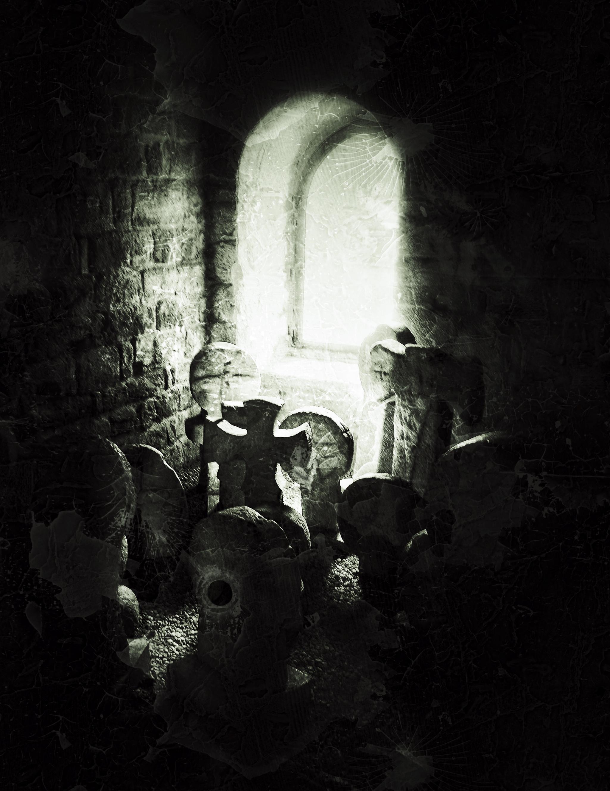 An illuminated window with shapes of thumbstones in the foreground