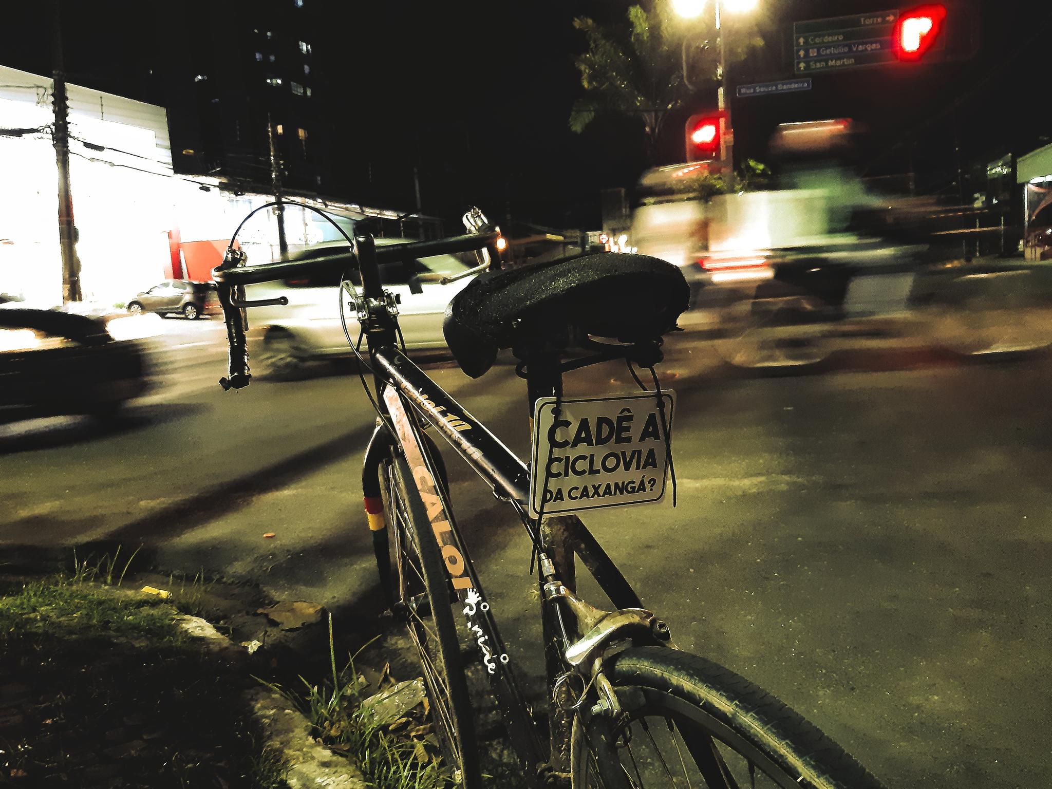 Bicicleta parada numa avenida com uma placa presa escrito cade a ciclovia da caxanga
