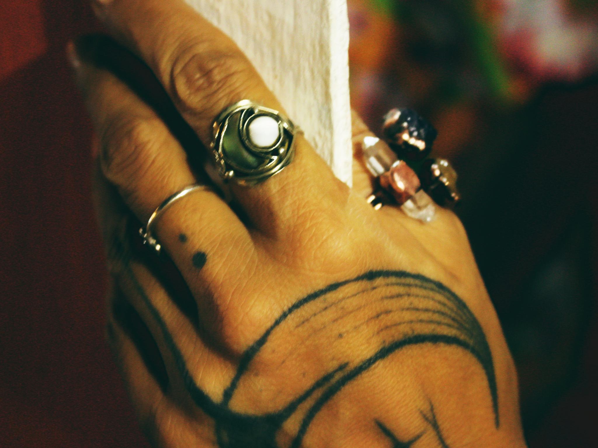 Mão com tatuagem de lua usando anéis