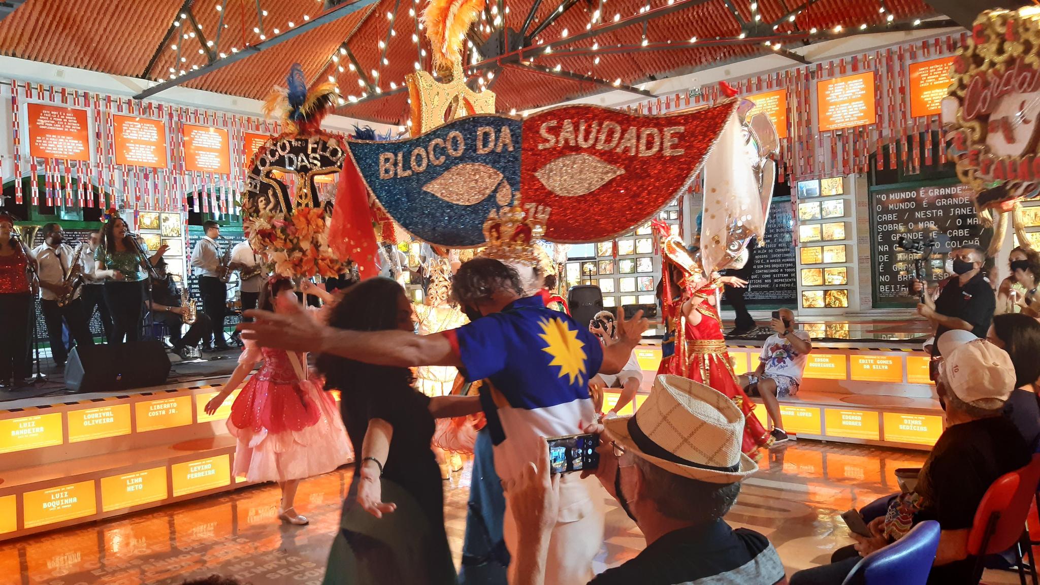Um homem e uma mulher dançando frevo no paço do frevo com o flabelo do Bloco da saudade