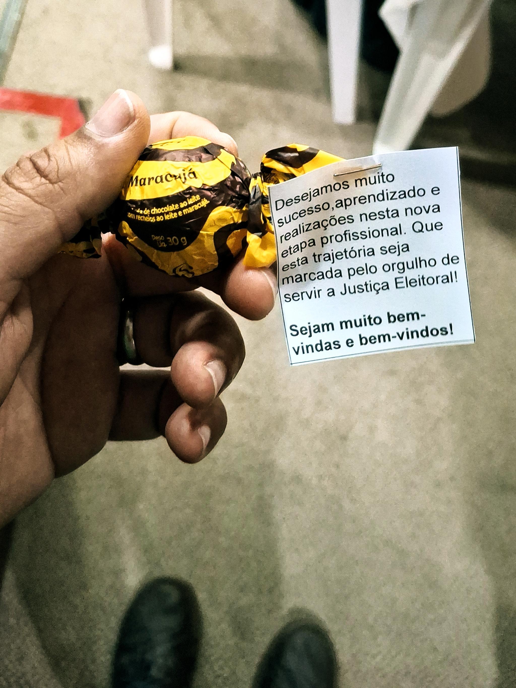 Mão segurando um bombom com uma mensagem de boas vindas