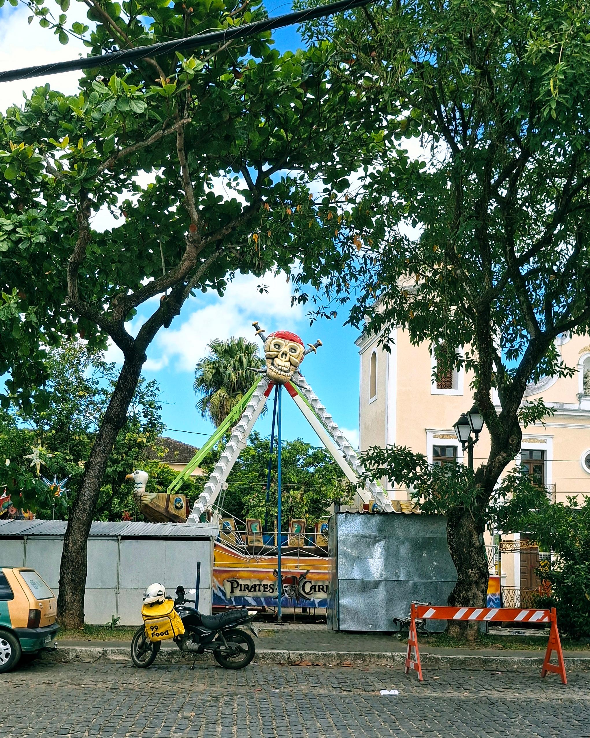 Rua com um brinquedo de parque de diversões com uma caveira pirata