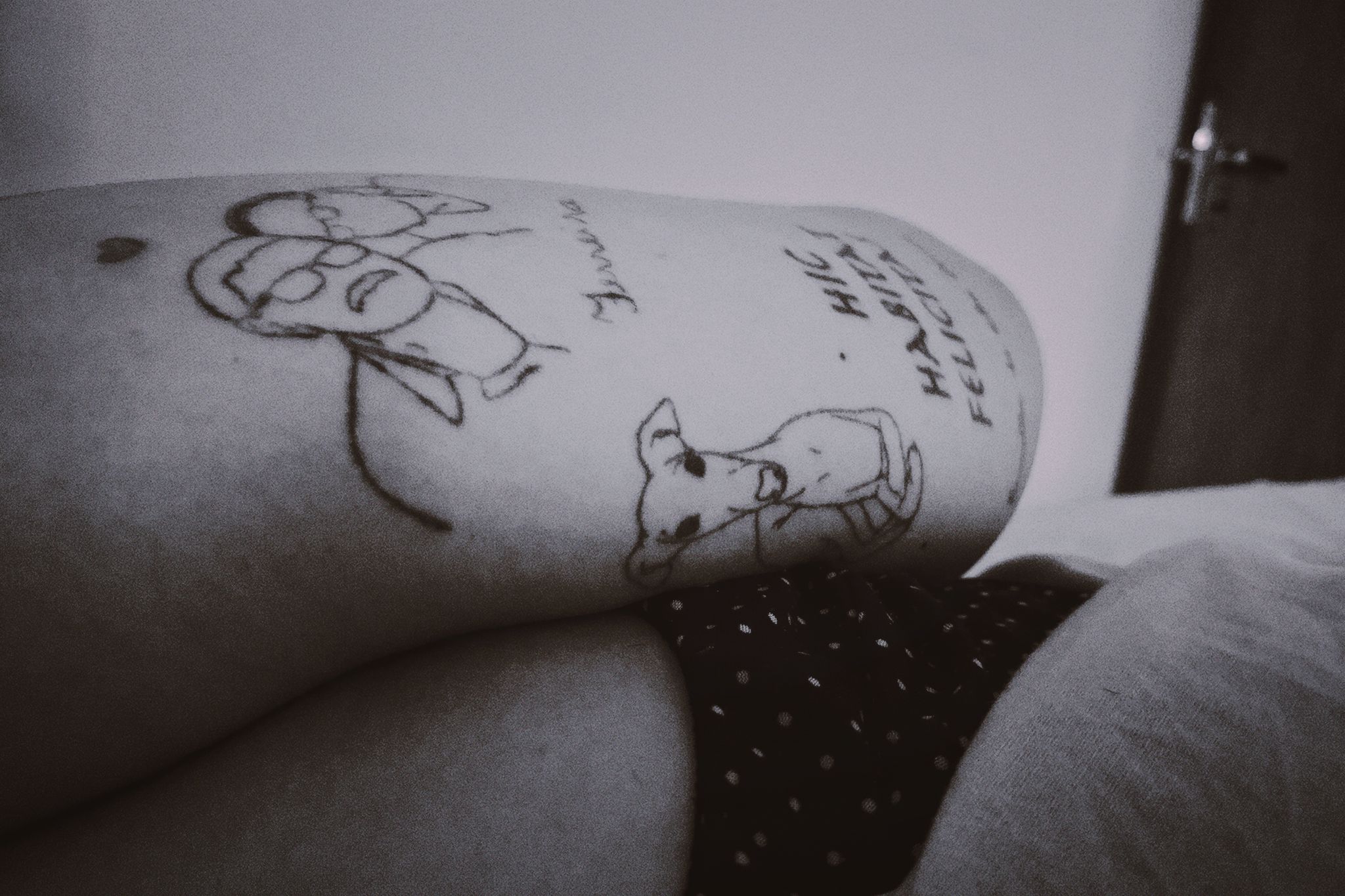 Braço tatuado. Uma tatuagem de cachorro e outra de um casal idoso