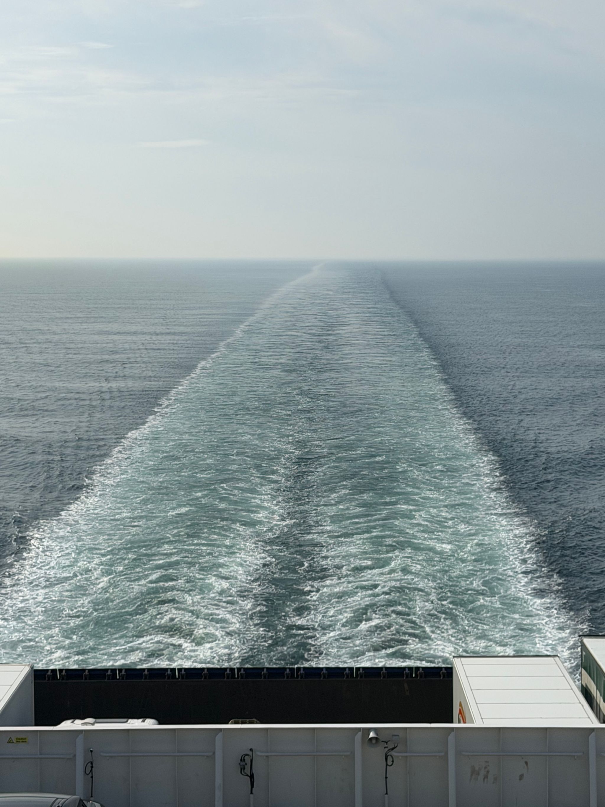 The churned sea at the back of a boat leading off into the horizon