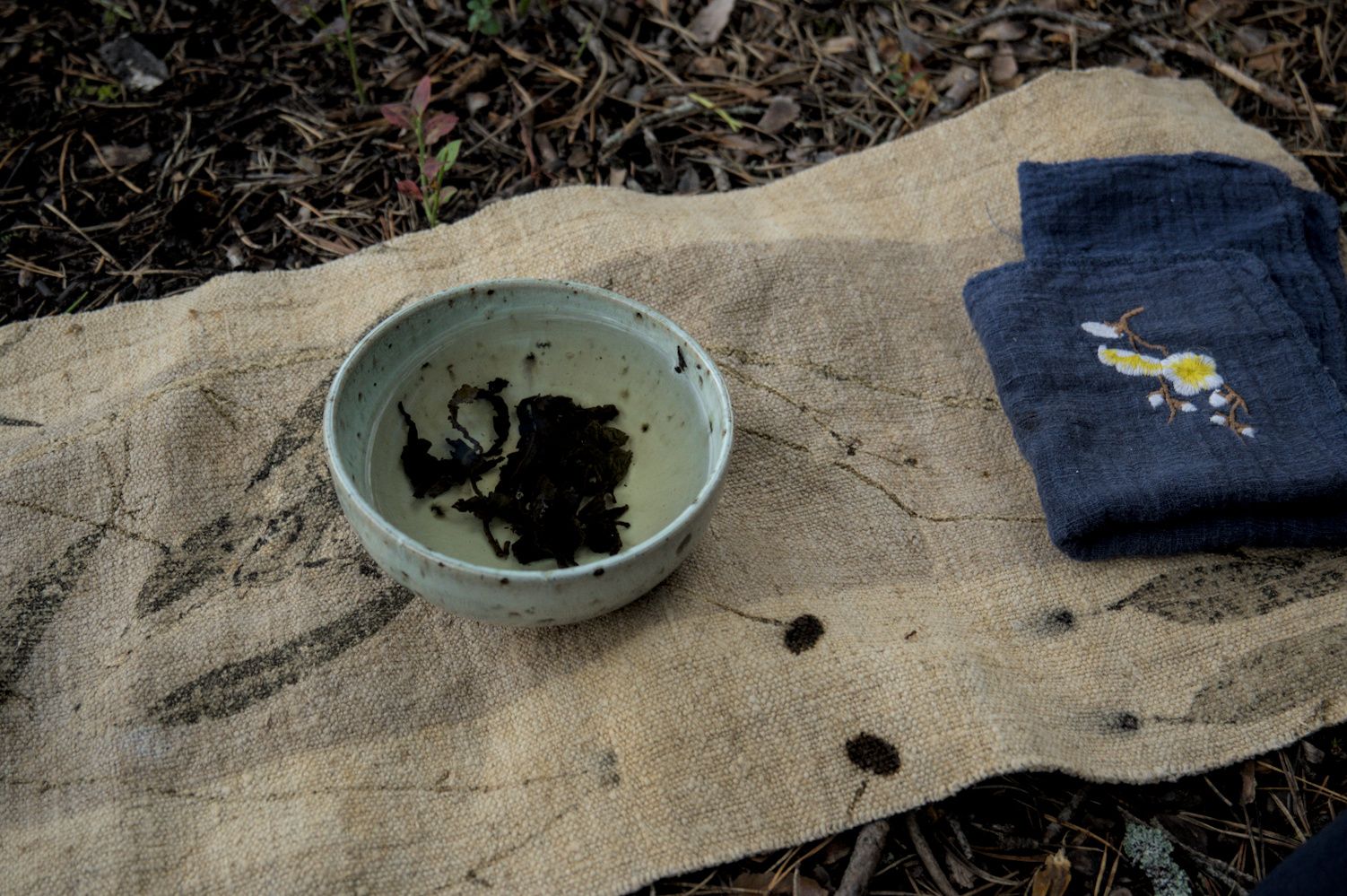 Tea in a bowl, with a blue tea cloth, on a natural linen runner