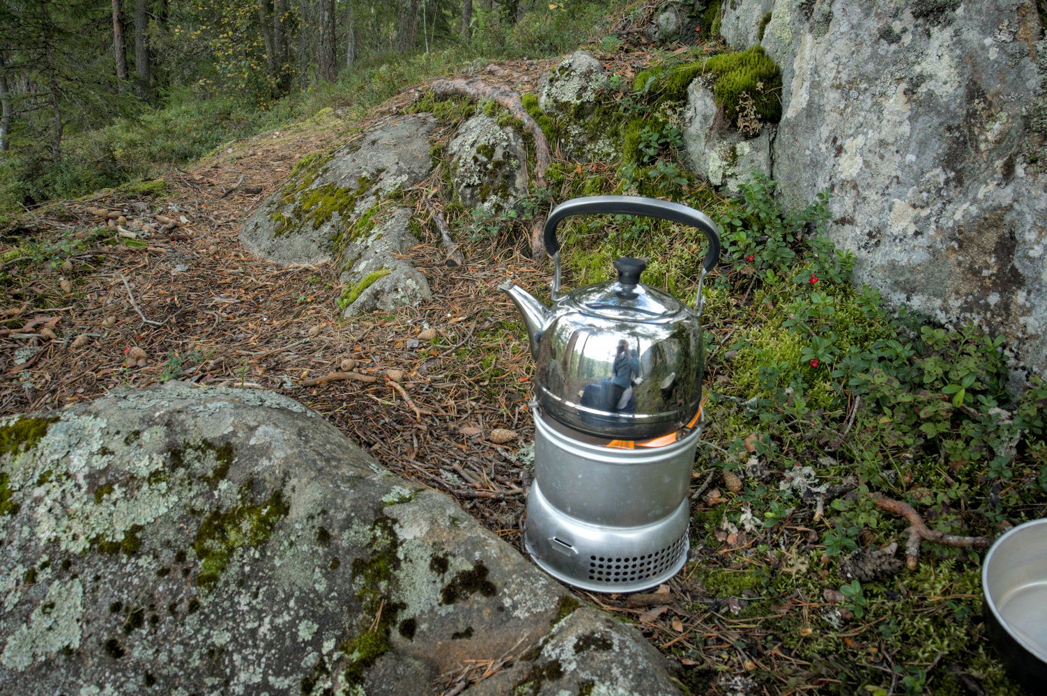 A stainless steel tea pot on a camping stove