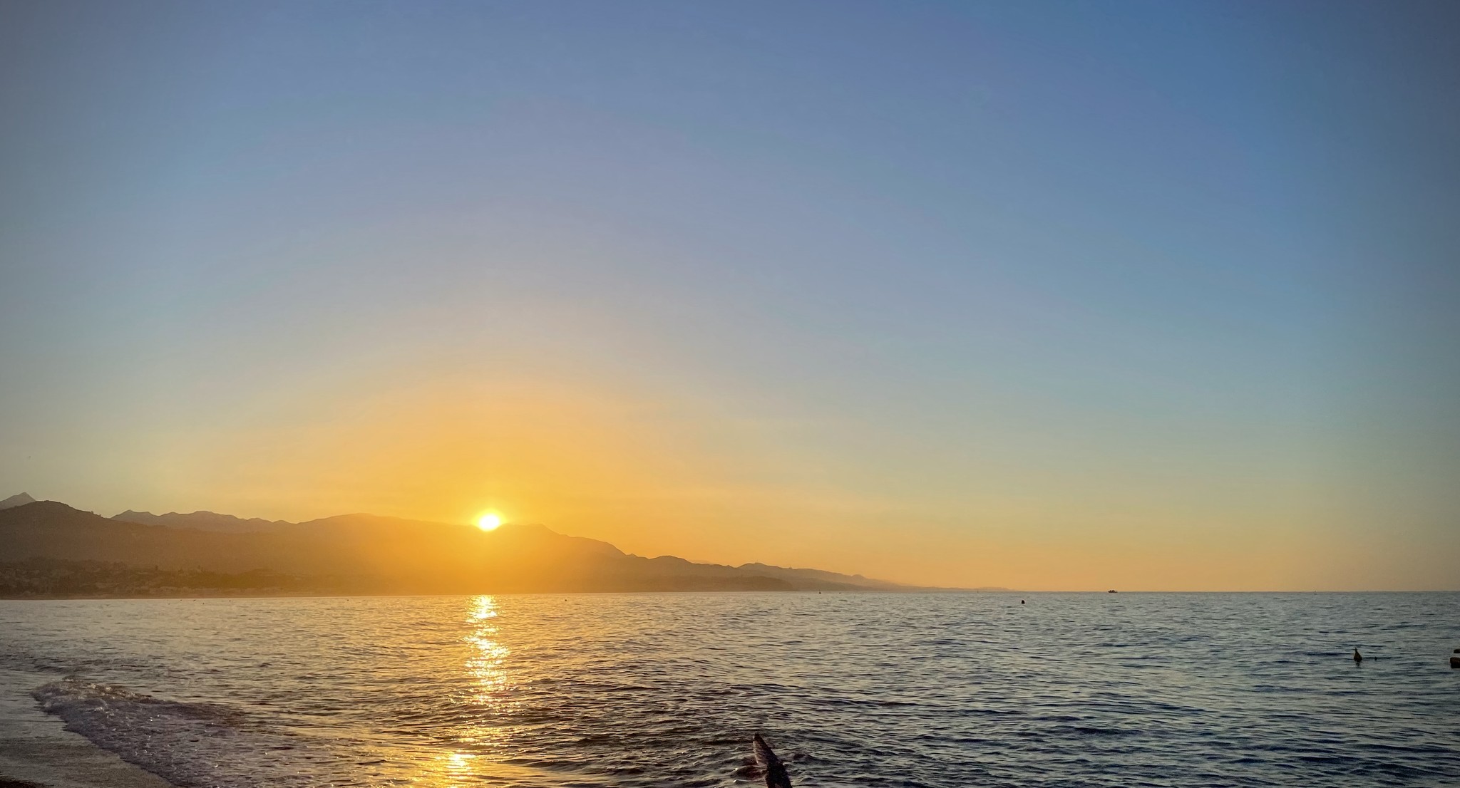 The sun rises over the Sierras de Tejeda, Almijara & Alhama and the Mediterranean Sea in Torre del Mar, Spain.