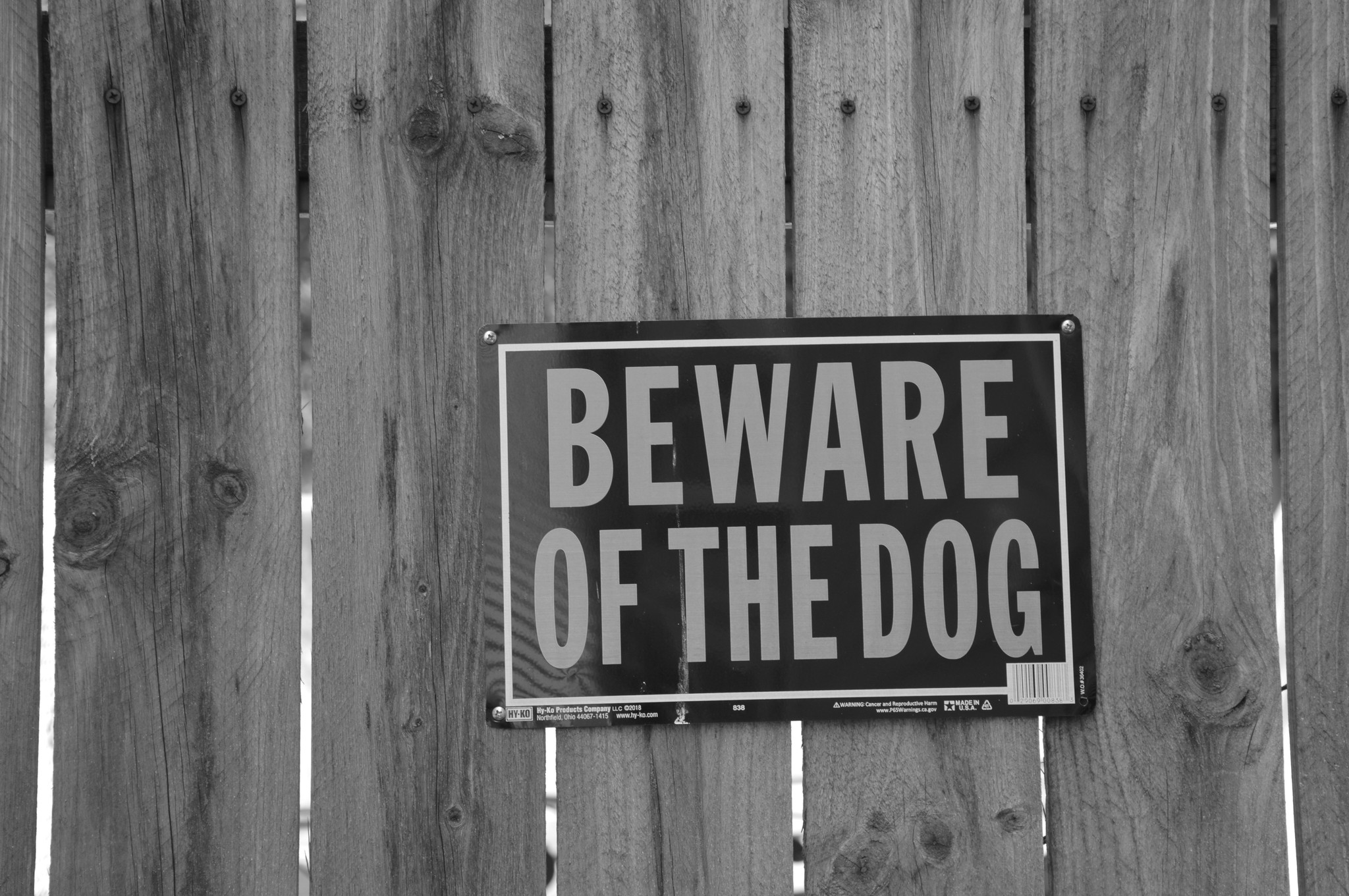 a weather worn wooden fence with a sign on it that says "Beware of the dog" in all capital letters